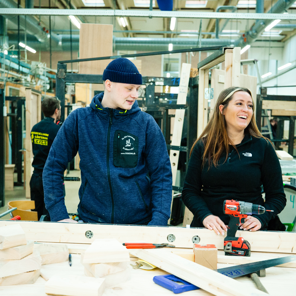 To personer arbejder ved en arbejdsbænk med værktøj og materialer, teamwork, arbejdsbænk, værktøj, materialer, værksted