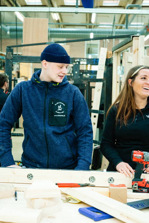 To personer arbejder ved en arbejdsbænk med værktøj og materialer, teamwork, arbejdsbænk, værktøj, materialer, værksted