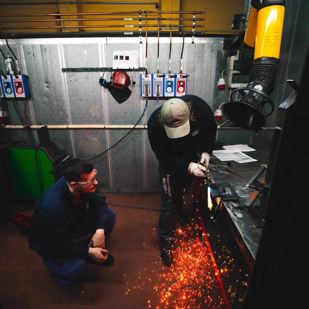 Lærling skærer metal med gnister i værksted, lærling, metalskæring, gnister, smedeuddannelsen, værksted, metalarbejde, erhvervsskole.