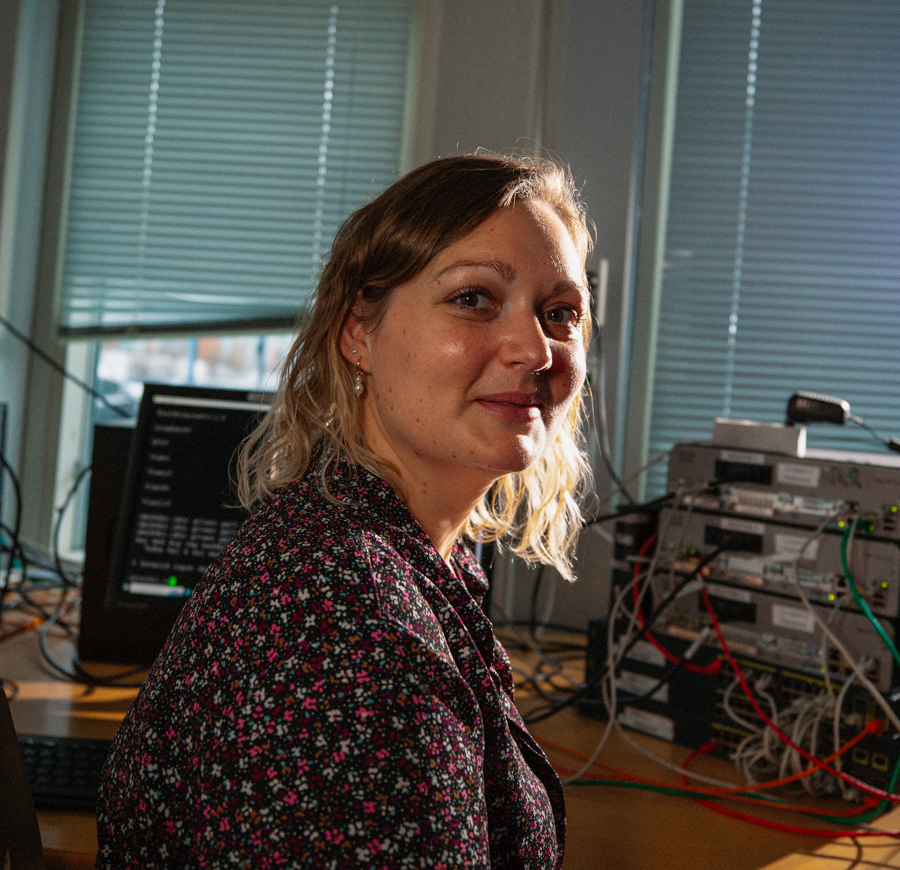 Kvinde arbejder ved en computer med netværksudstyr i baggrunden, data og kommunikation, IT-uddannelse, netværksudstyr, kvinde ved computer