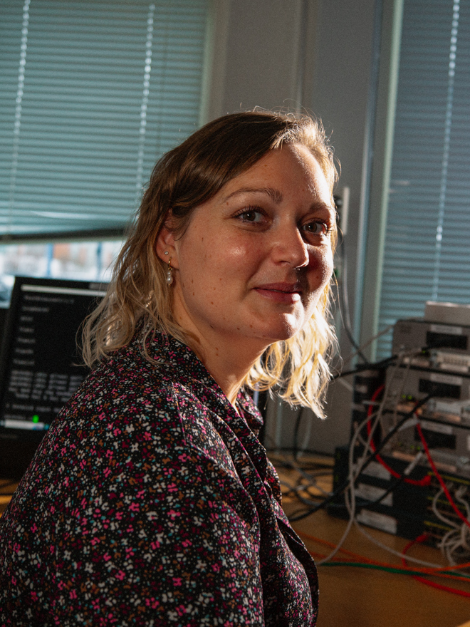 Kvinde arbejder ved en computer med netværksudstyr i baggrunden, data og kommunikation, IT-uddannelse, netværksudstyr, kvinde ved computer