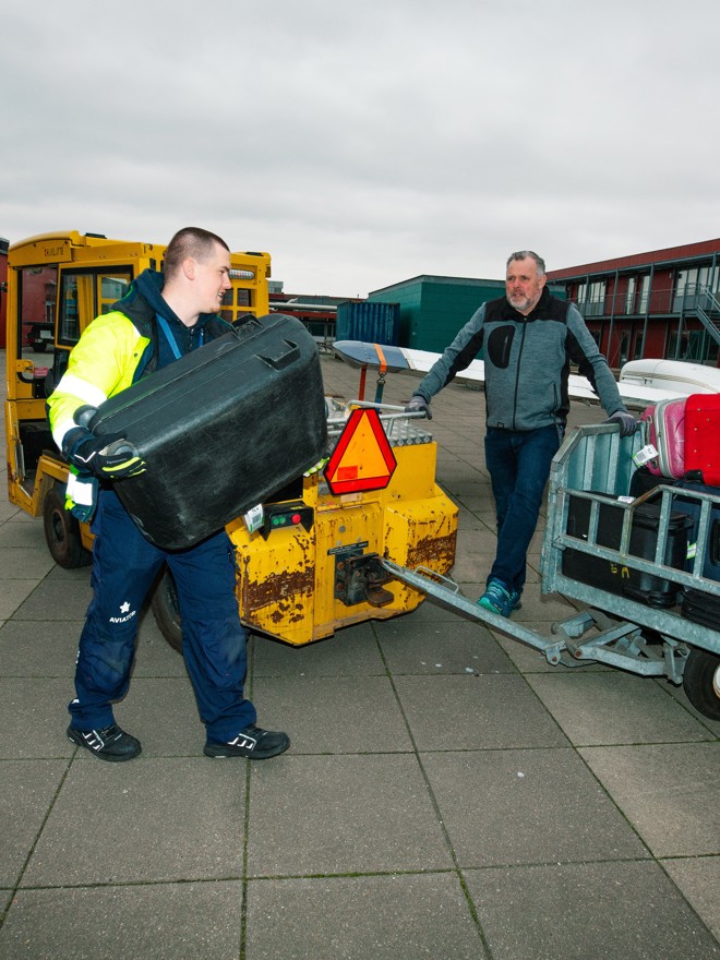 Lærling håndtere bagage, Bagagehåndtering, lufthavn, transport, sikkerhedsvest, udendørs arbejde, logistik, bagagevogn.