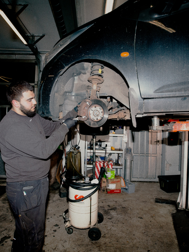 Lærling arbejder med tungt udstyr i et bilværksted på en erhvervsskole, Lærling, tungt udstyr, bilværksted, personvognsmekaniker, mekanikeruddannelse, erhvervsskole, bilreparation.