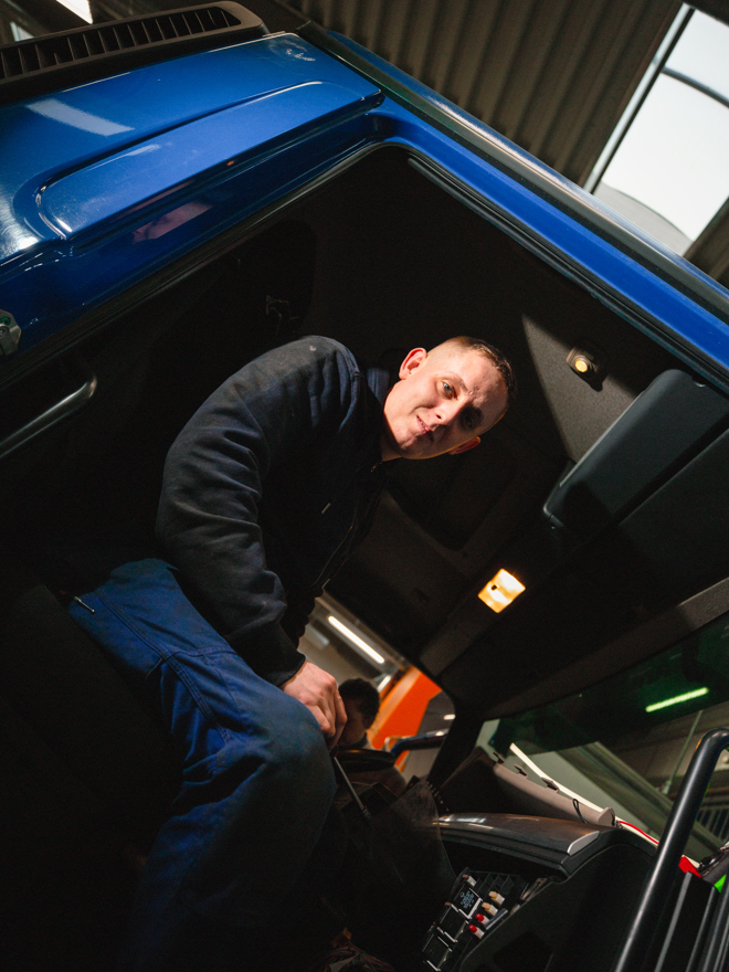 Mekaniker går op i førerkabinen på en blå lastbil, mekaniker, førerkabine, blå lastbil, indstigning