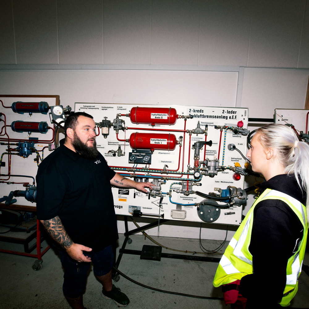 To personer snakker i et teknisk træningsmiljø med udstyr, teknisk træning, diskussion, vejgodstransport, udstyr, samarbejde