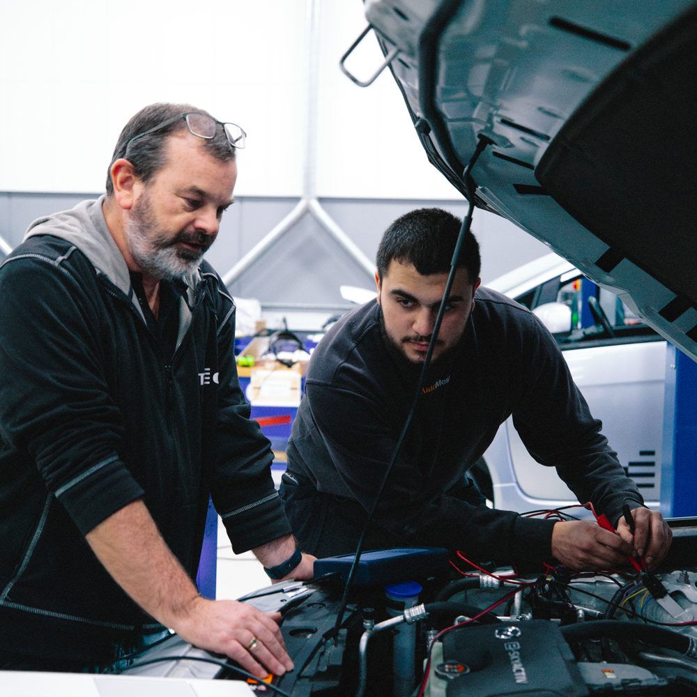 To mekanikere arbejder sammen på en motor i værkstedet, mekanikere, motor, samarbejde, værksted, reparation