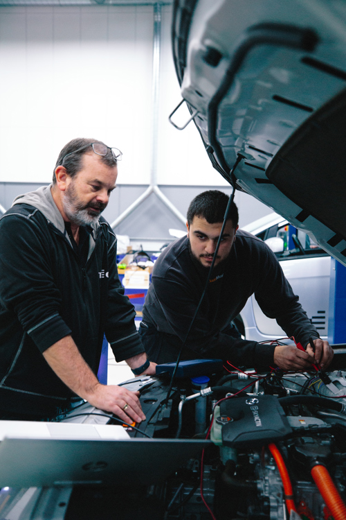 To mekanikere arbejder sammen på en motor i værkstedet, mekanikere, motor, samarbejde, værksted, reparation