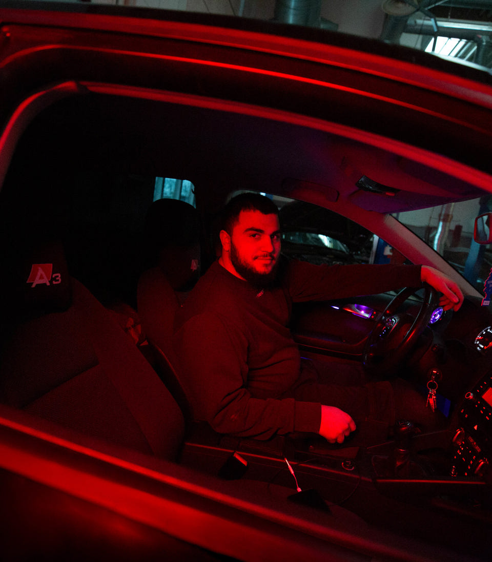 Lærling sidder i førersædet af en bil,  lærling, bilinteriør, rødt lys, værksted, personvognsmekaniker  mekanikeruddannelse, bilreparation, erhvervsskole