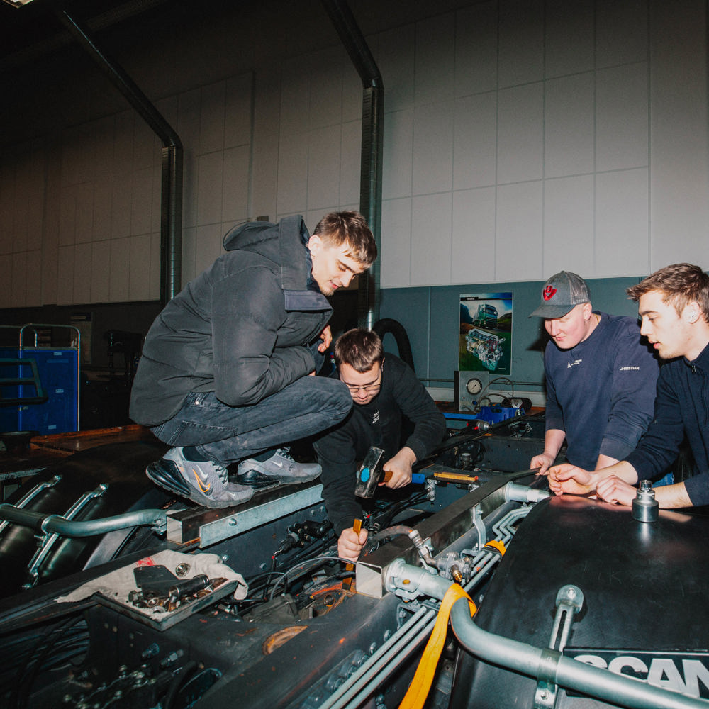 Gruppe lærlinge diskuterer reparation af motor,  lastvognsmekanikeruddannelsen, gruppediskussion, motorreparation, lærling