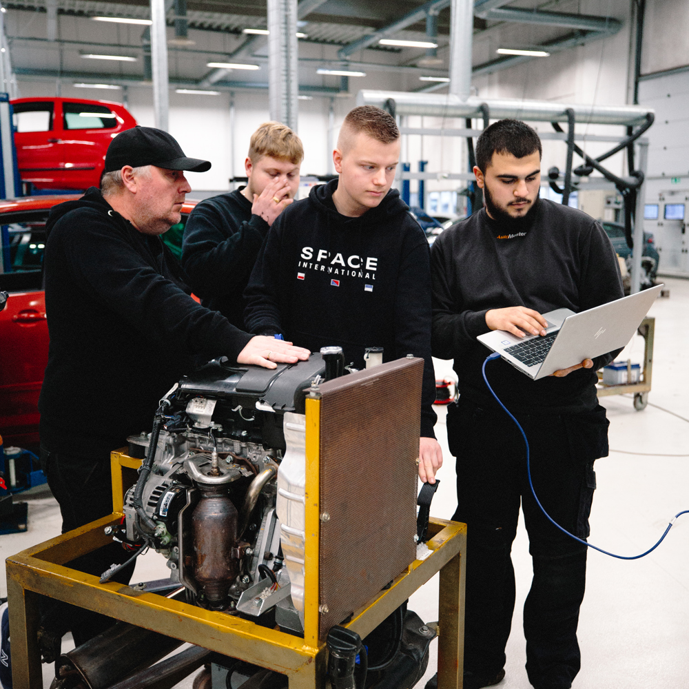 Gruppe af mekanikere arbejder sammen om en motor i værkstedet, mekanikere, motor, værksted, teamwork, reparation