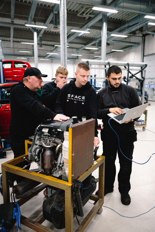 Gruppe af mekanikere arbejder sammen om en motor i værkstedet, mekanikere, motor, værksted, teamwork, reparation
