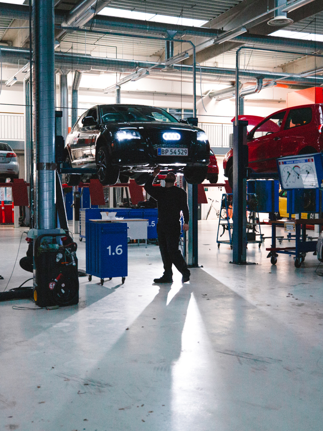 Biler og mekanikere arbejder i et stort værksted med lifte, mekanikere, værksted, lifte, reparation