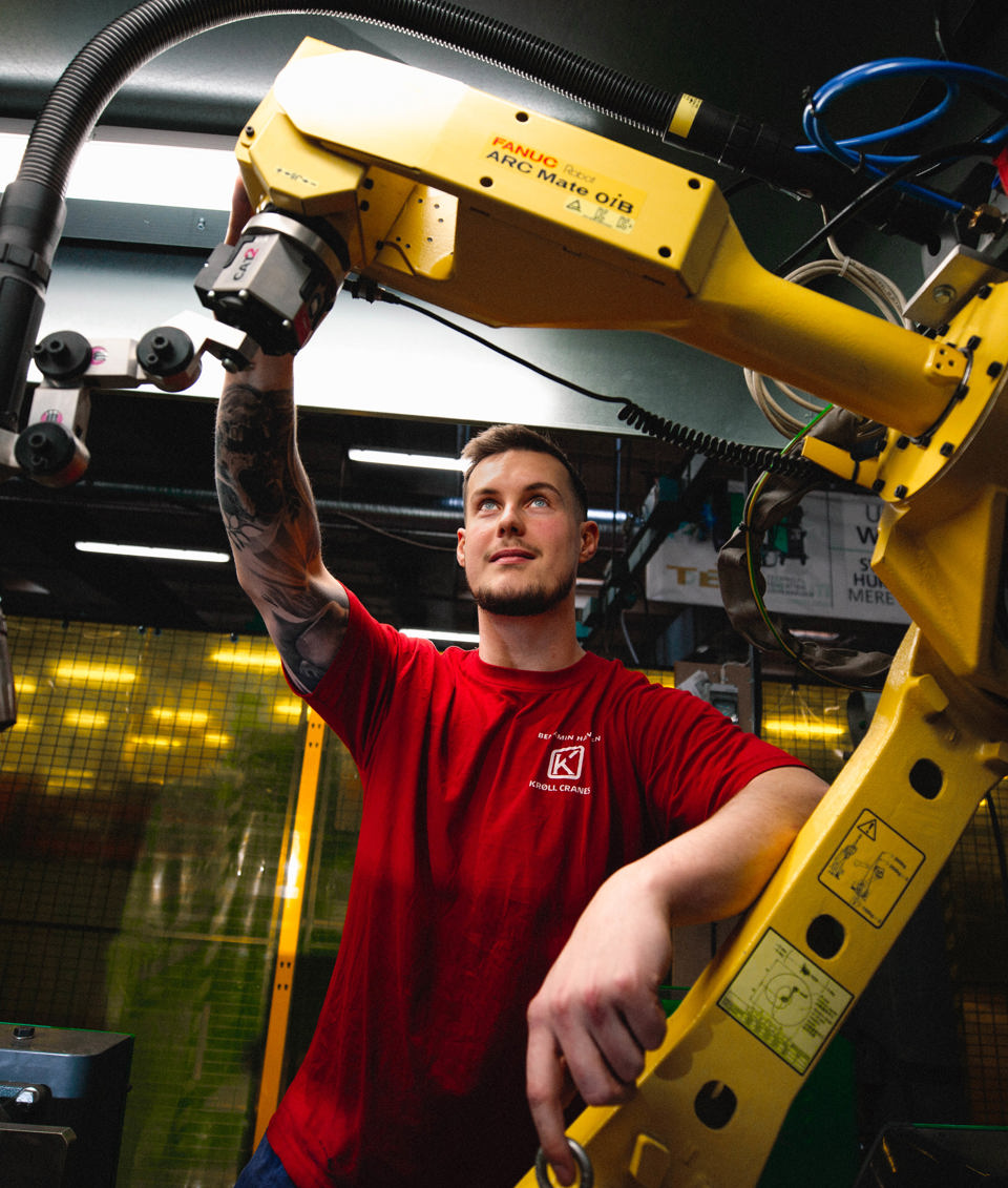 Lærling arbejder med industriel robotarm, lærling, industriel robotarm, værksted, smedeuddannelsen, automation, metalarbejde, erhvervsskole.