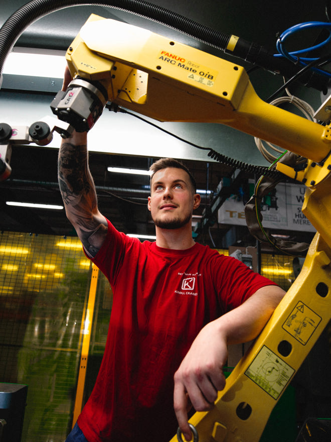Lærling arbejder med industriel robotarm, lærling, industriel robotarm, værksted, smedeuddannelsen, automation, metalarbejde, erhvervsskole.