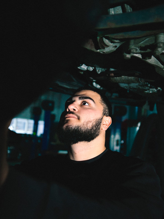 Mekaniker arbejder under en bil i værkstedet, bilreparation, værksted, inspektion, lift