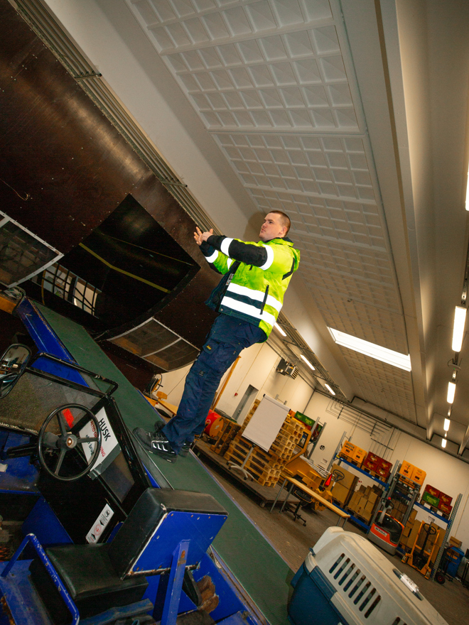 Person flytter bagage i lastrum ved hjælp af transportbånd, Bagagehåndtering, lastrum, lufthavn, transportbånd, logistik, transport, sikkerhedsvest, lufthavnsuddannelsen.