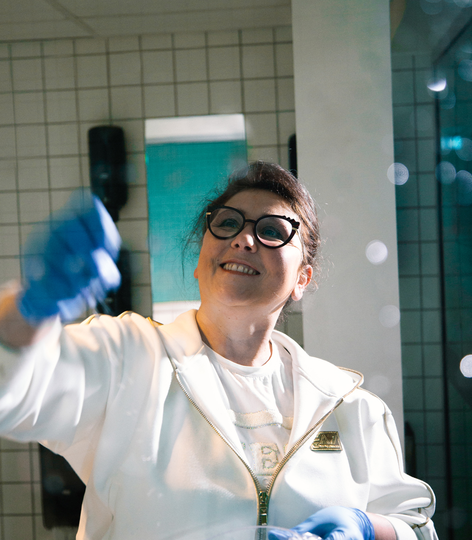 Rengøringstekniker pudser spejl i badeværelse, rengøringstekniker, spejl, pudsning, rengøringsteknikeruddannelsen, badeværelse, rengøringsarbejde, erhvervsskole.