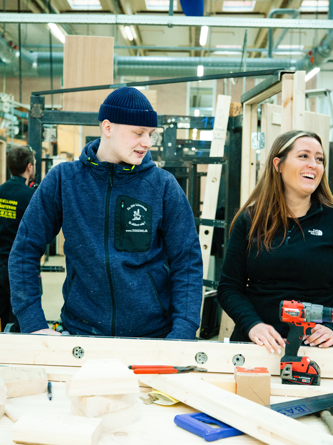 To personer arbejder sammen ved en arbejdsbænk med værktøj og materialer i værkstedet, arbejdsbænk, værktøj, materialer, værksted