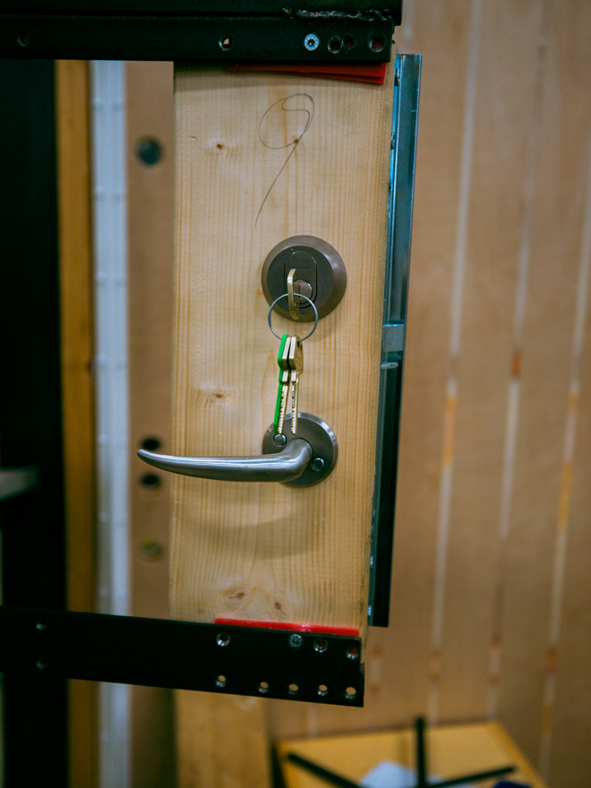 Nærbillede af en dør med monteret håndtag og lås i værkstedet, håndtag, lås, værksted, montering