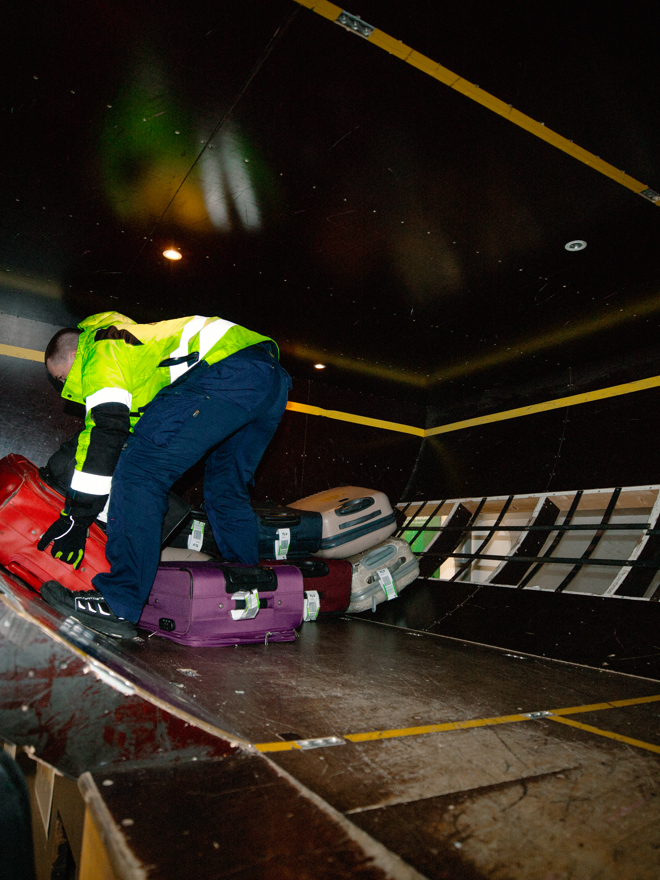 Personer arrangerer bagage i bagagerum I flyvemaskine, Bagagehåndtering, lufthavn, bagagerum, logistik, teamwork, transport, opbevaring, lufthavnsuddannelsen