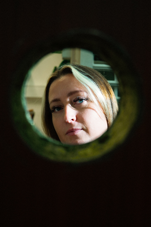 Kvinde kigger gennem et kighul i en dør i et værksted, kighul, dør, værksted, indblik